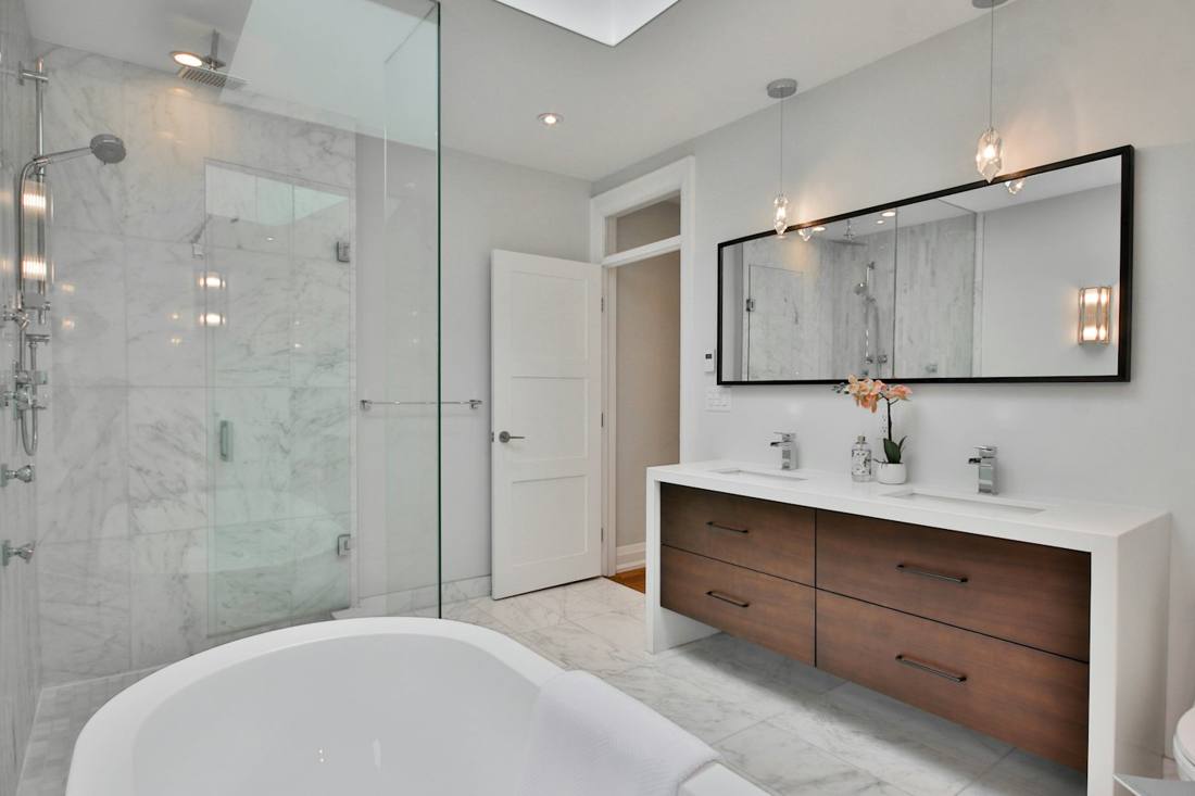 Baño con ducha de obra acristalada y mueble de lavabo de madera